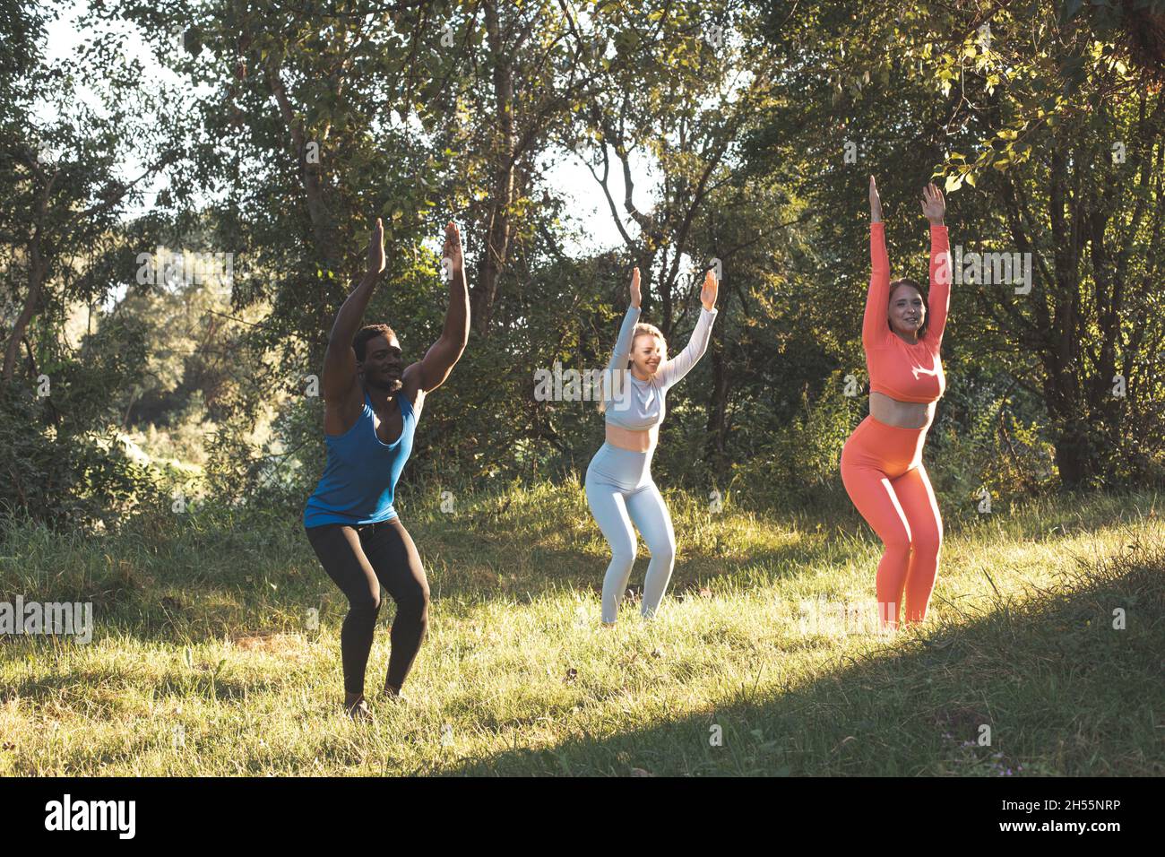 Die jungen, vielfältigen Menschen praktizieren Yoga in der Natur Stockfoto