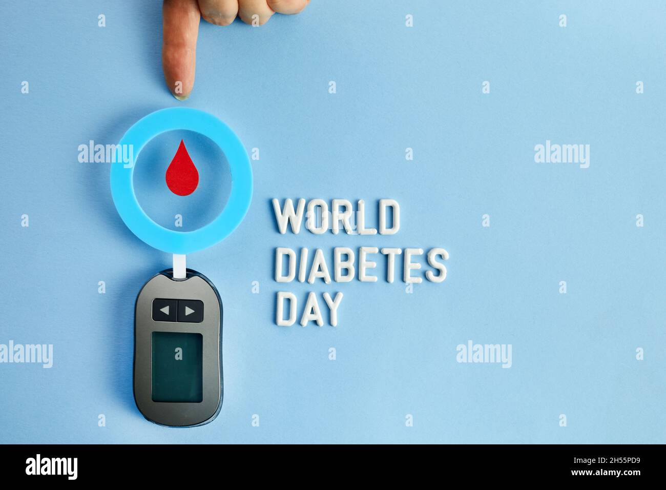 Konzept des Welt-Diabetes-Tages. Roter Blutstropfen im Kreis mit Blutzuckerteststreifen und Blutzuckermessgerät. Draufsicht Stockfoto