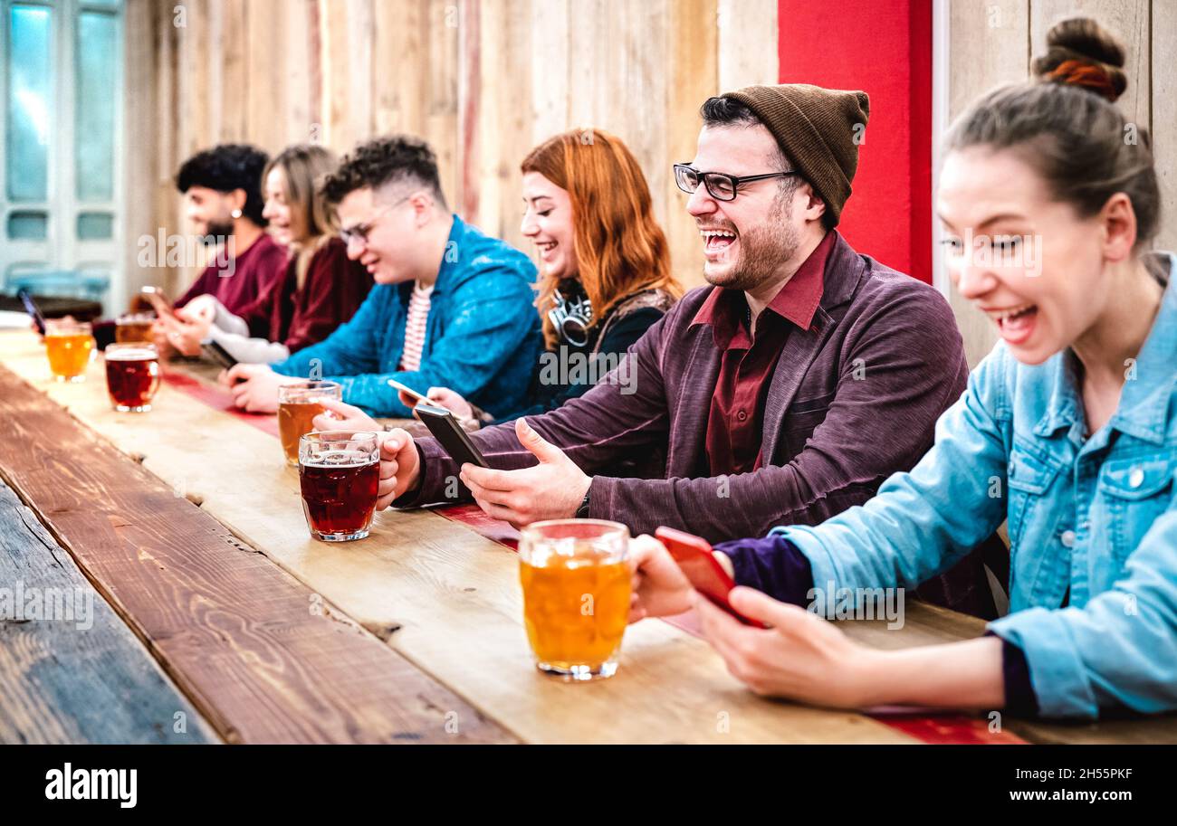 Multikulturelle Freunde, die Bier trinken und Spaß mit mobilen Smartphones im Bierlokal der Brauerei haben - Social Gathering Konzept Stockfoto