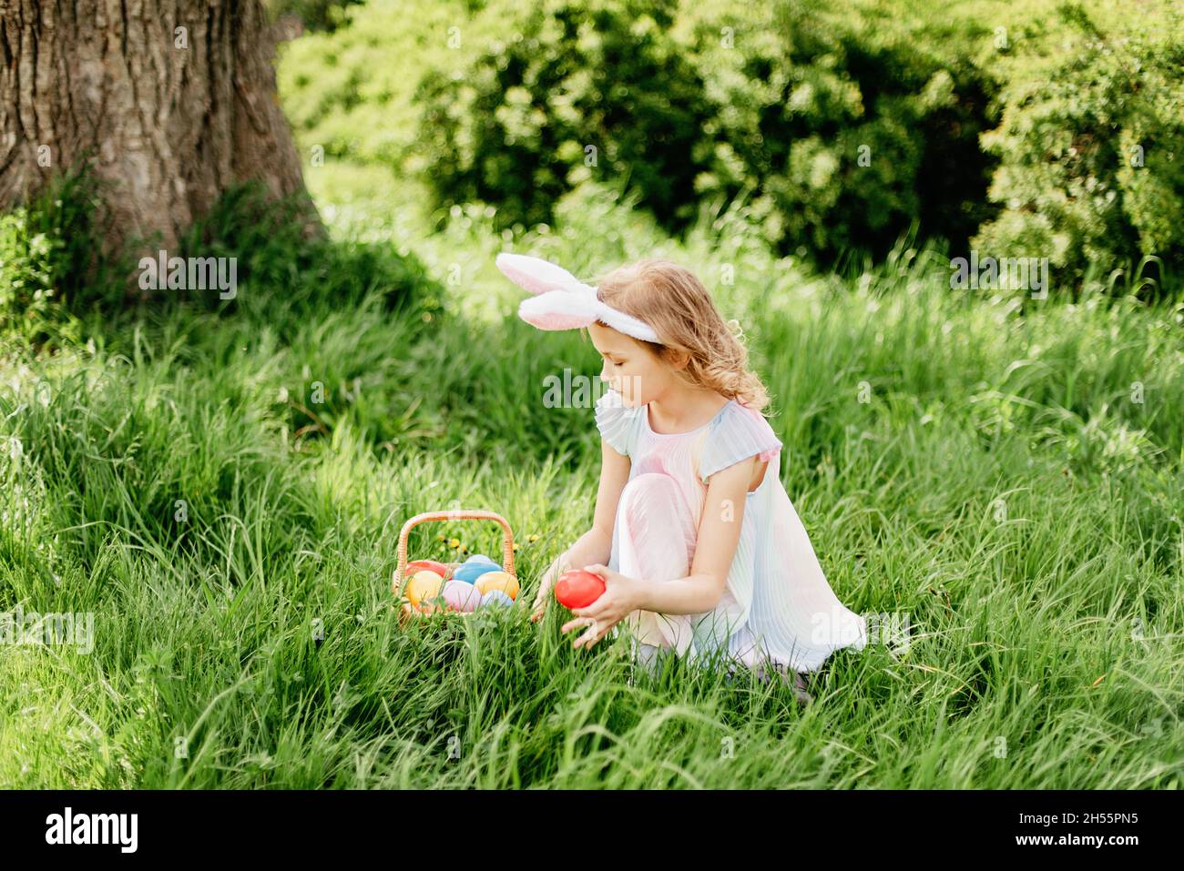Ostereiersuche. Mädchen Kind trägt Bunny Ohren laufen, um Ei im Garten  abholen. Ostertradition. Lachende Kinder im Park mit Korbfederkonzept  Stockfotografie - Alamy