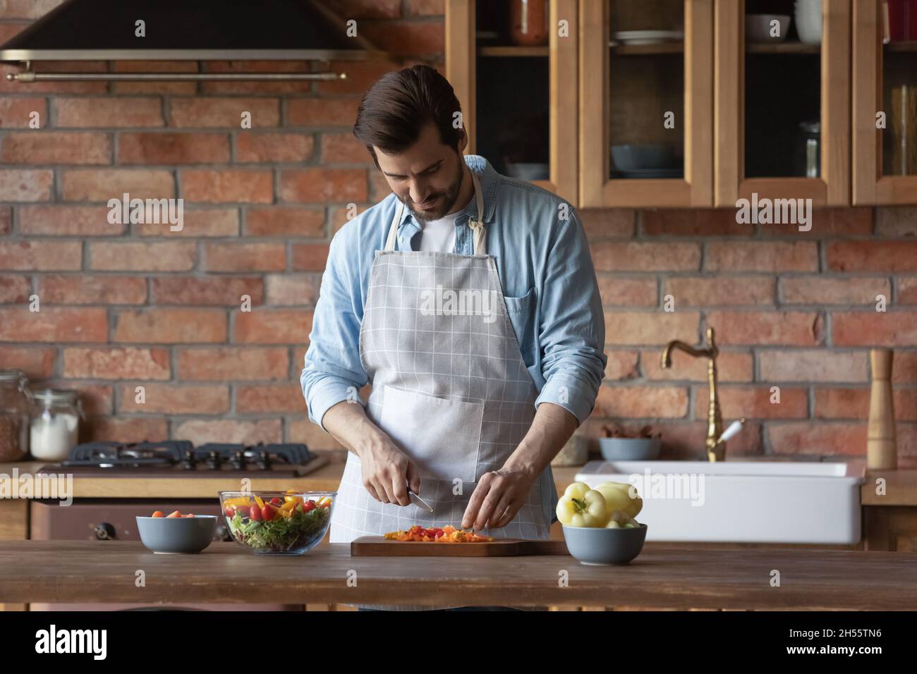 Millennial männlich trägt Küchenschürze kochen diätetischen Salat zum Frühstück Stockfoto