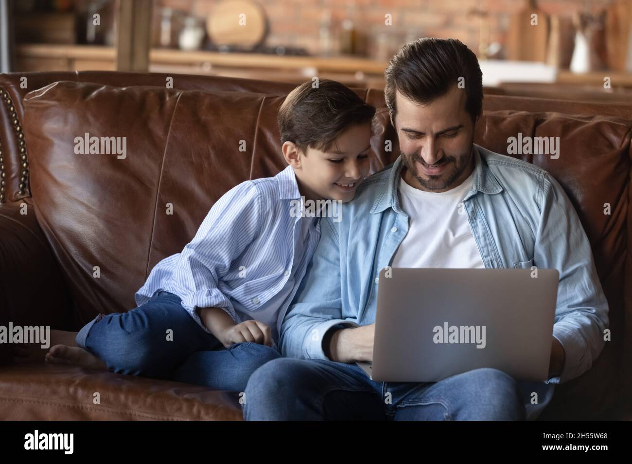 Der Teenager Junge spielt mit seinem erwachsenen älteren Bruder ein Spiel auf dem Laptop Stockfoto