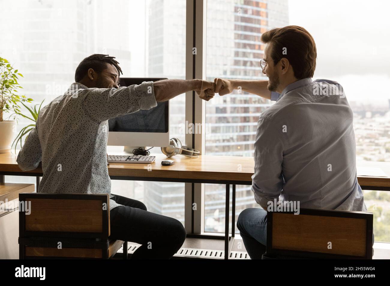 Glückliche zwei gemischte Rennen männlichen Kollegen stoßen Fäuste. Stockfoto