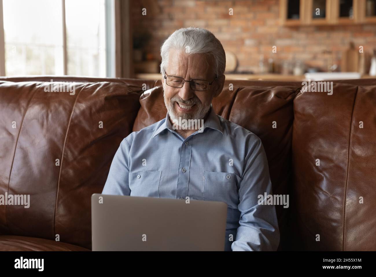 Lächelnde ältere Männer, die eine Brille tragen, sehen auf dem Laptop-Bildschirm aus Stockfoto