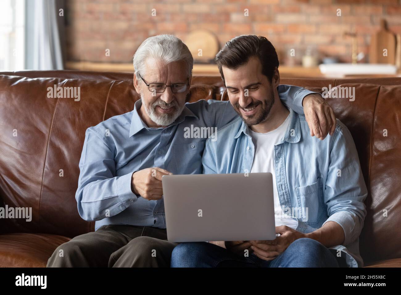 Ältere und jüngere Männer, Verwandte umarmen sich auf dem Laptop-Bildschirm Stockfoto