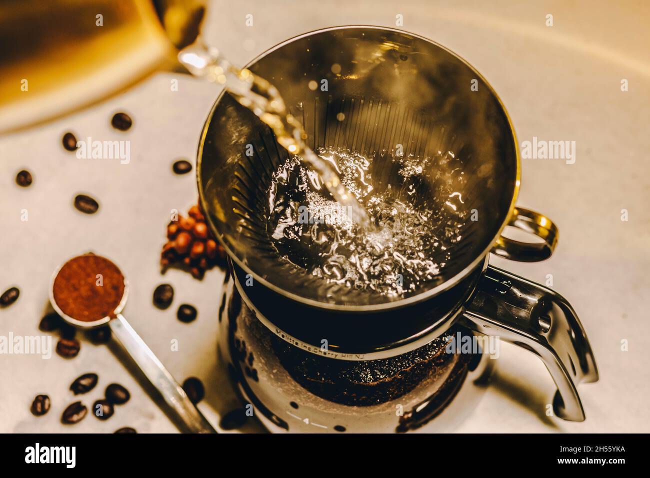 Kaffee mit einem Filtertropfer zubereiten. Extreme Nahaufnahme des Gießens von heißem kochendem Wasser in die Kaffeemaschine aus Glas Stockfoto