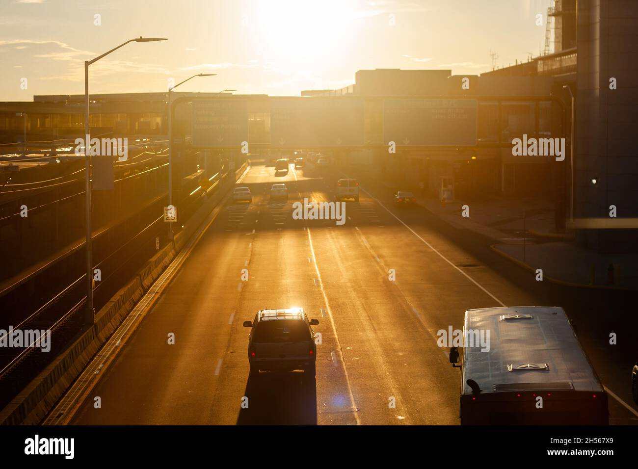 Straße bei Sonnenaufgang mit Autos, die gegen die helle Sonne fahren | wunderschöne Szene, sonnendurchflutete Straße am Morgen Blick von oben, Autos, die in Richtung Sonne fahren Stockfoto