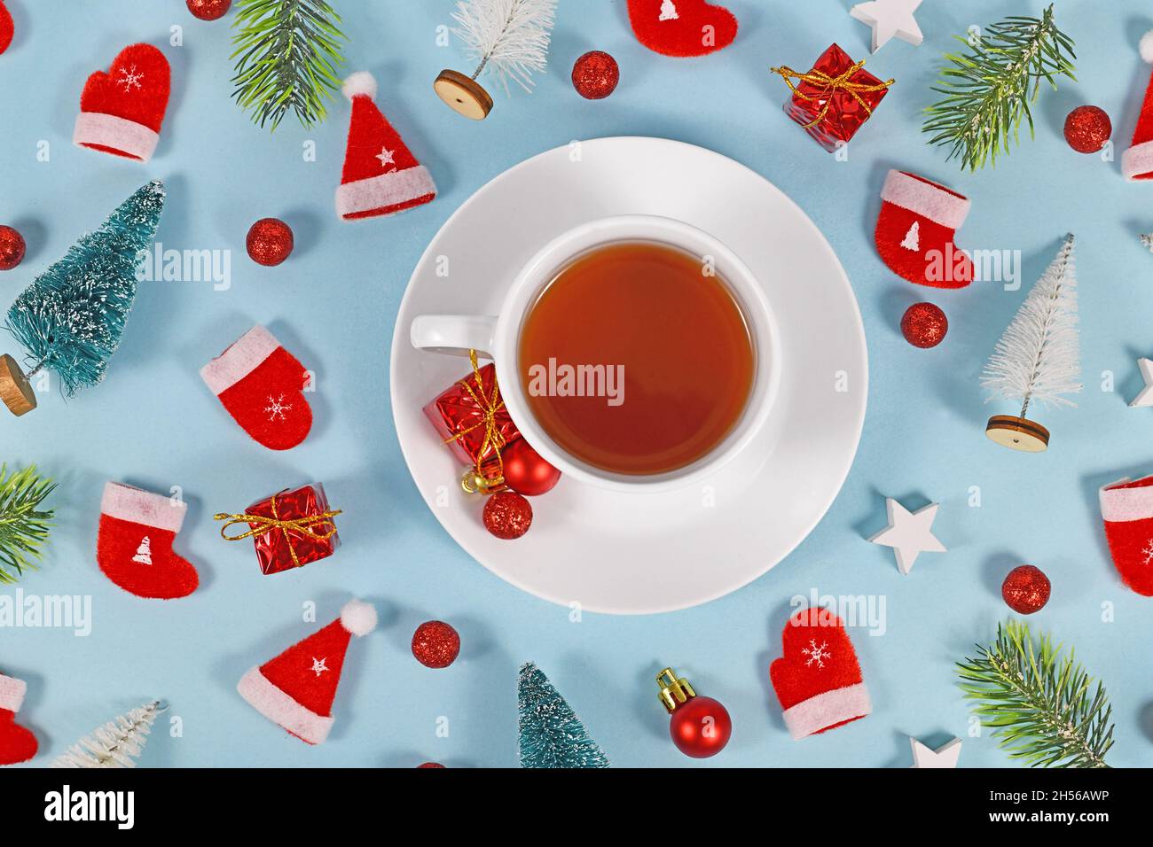 Teetasse umgeben von weihnachtlicher Dekoration auf blauem Hintergrund Stockfoto