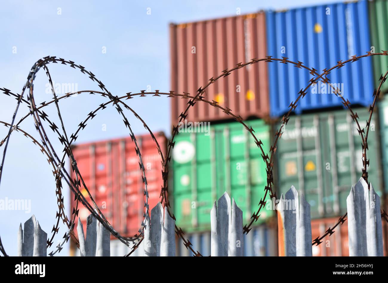 Frachtcontainer stapelten sich hoch hinter einem Stacheldraht-Zaun an einem der verkehrsreichsten Häfen Großbritanniens in Southampton. Stockfoto