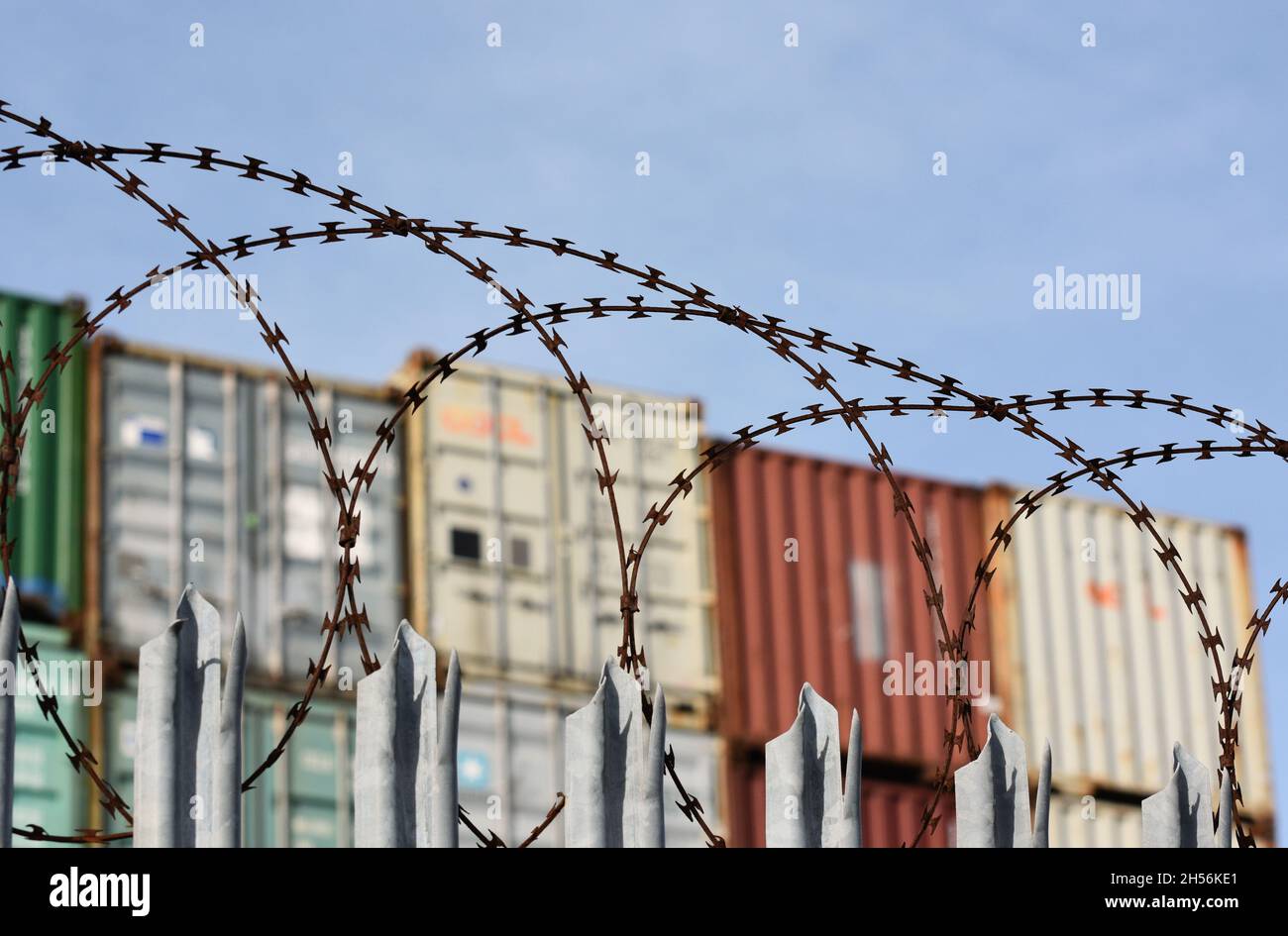 Frachtcontainer stapelten sich hoch hinter einem Stacheldraht-Zaun an einem der verkehrsreichsten Häfen Großbritanniens in Southampton. Stockfoto