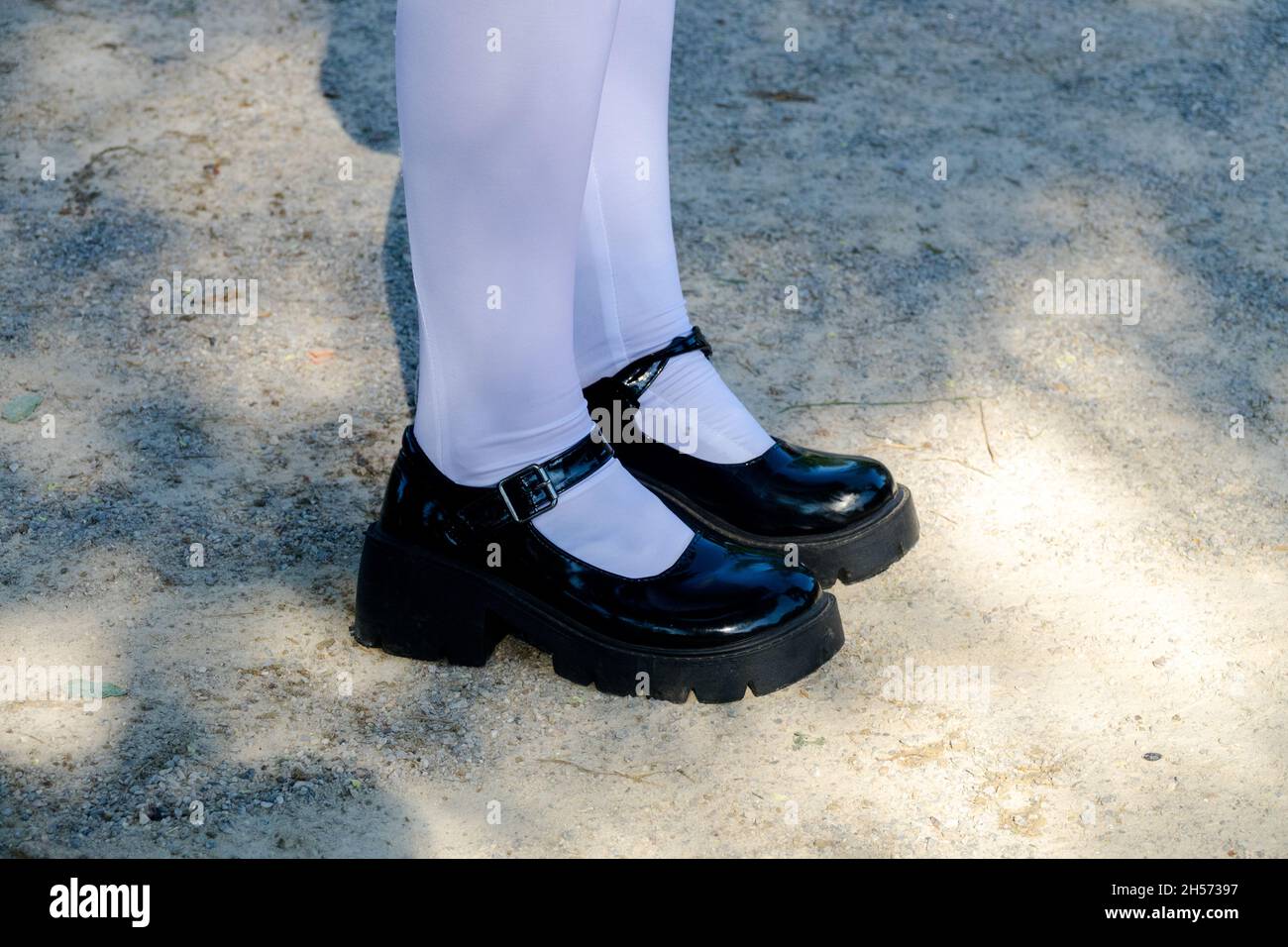 Ein Mädchen im Teenageralter in schwarzen Schuhen mit weißen Socken Stockfoto