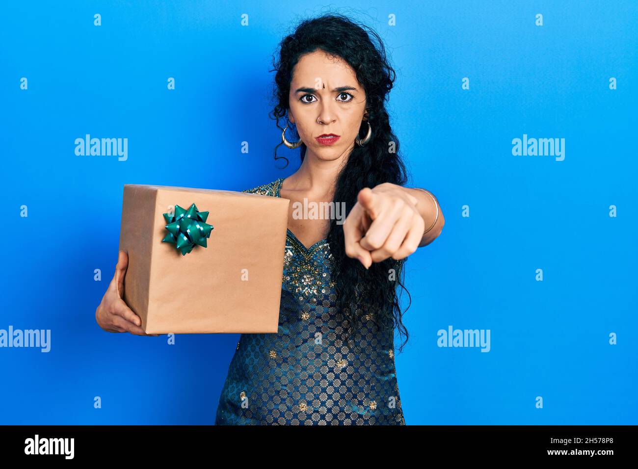 Junge Frau trägt Bindi und traditionelle Kurta Kleid halten Geschenk zeigt mit dem Finger auf die Kamera und Sie, selbstbewusste Geste, die ernst Stockfoto