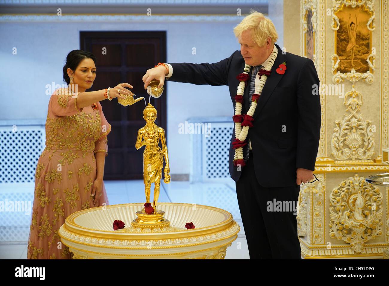 Premierminister Boris Johnson und Innenminister Priti Patel gießen Wasser über ein vergoldetes Messingbild von Shri Nilkanth Varni (Bhagwan Swaminarayan) bei einer Abhishek-Zeremonie, während sie an den Diwali-Feierlichkeiten während ihres Besuchs im Hindu-Tempel, BAPS Shri Swaminarayan Mandir in Neasden, London, teilnehmen. Diwali, ein fünftägiges Lichterfest und eines der wichtigsten Feste, die von Hindus, Jains und Sikhs gefeiert werden. Bilddatum: Sonntag, 7. November 2021. Stockfoto