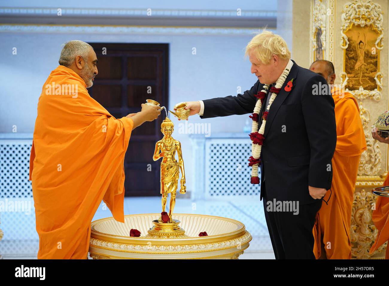 Premierminister Boris Johnson gießt Wasser über ein vergoldetes Messingbild von Shri Nilkanth Varni (Bhagwan Swaminarayan) in einer Abhishek-Zeremonie mit Leiter Sadhu Yogvivekdas Swami, während sie an den Diwali-Feiern während ihres Besuchs im Hindu-Tempel, BAPS Shri Swaminarayan Mandir in Neasden, London, teilnehmen. Diwali, ein fünftägiges Lichterfest und eines der wichtigsten Feste, die von Hindus, Jains und Sikhs gefeiert werden. Bilddatum: Sonntag, 7. November 2021. Stockfoto