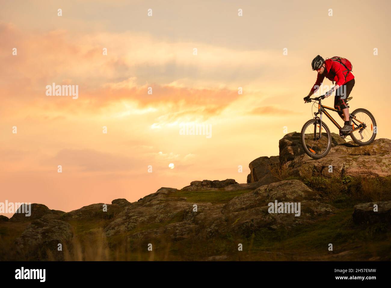 Radler in Red Riding Bike auf dem Sommer Rocky Trail bei Sonnenuntergang. Extreme Sport und Enduro Biking Konzept. Stockfoto