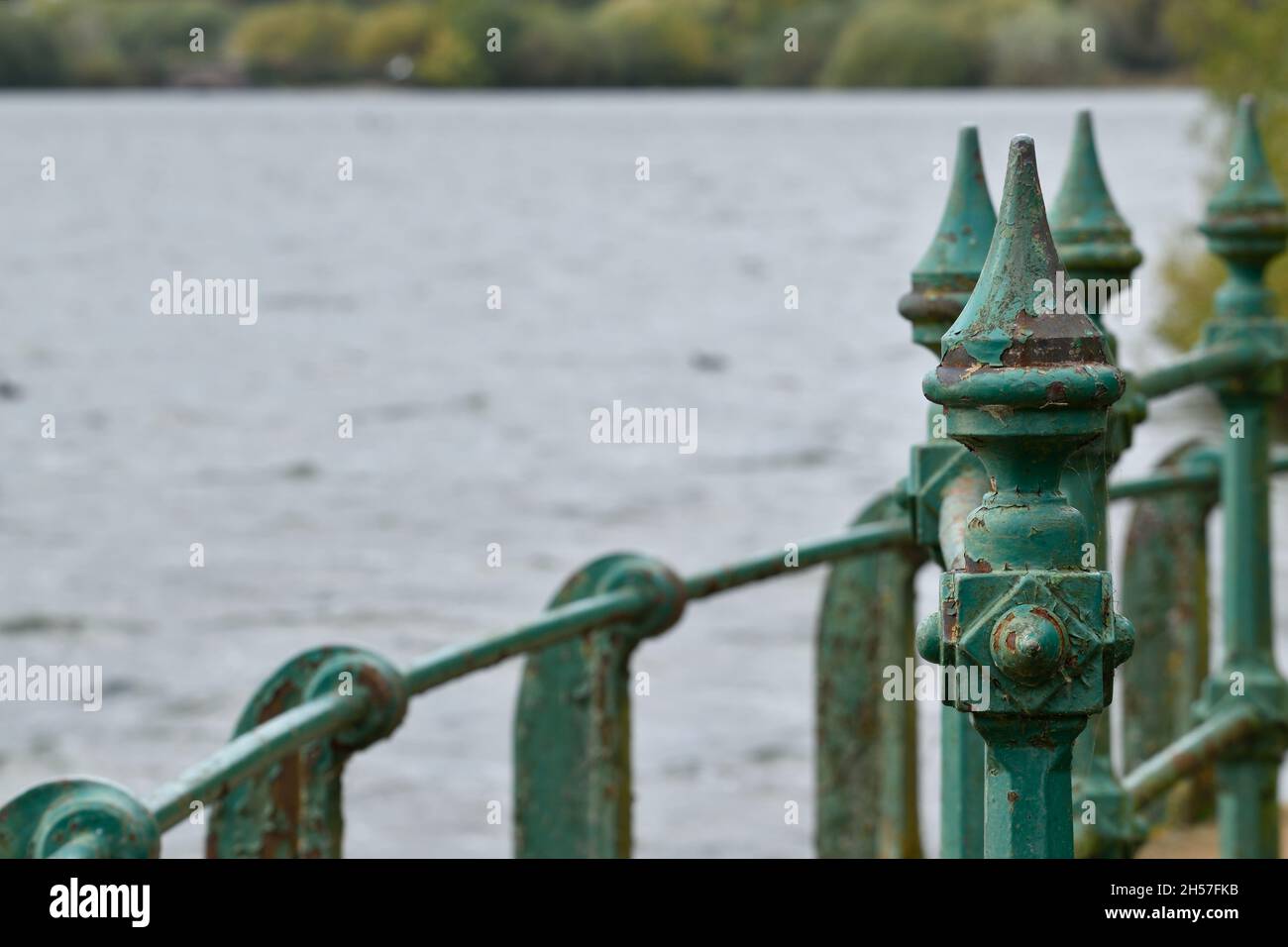 Grünes Metallbrückengeländer vor einem See Stockfoto