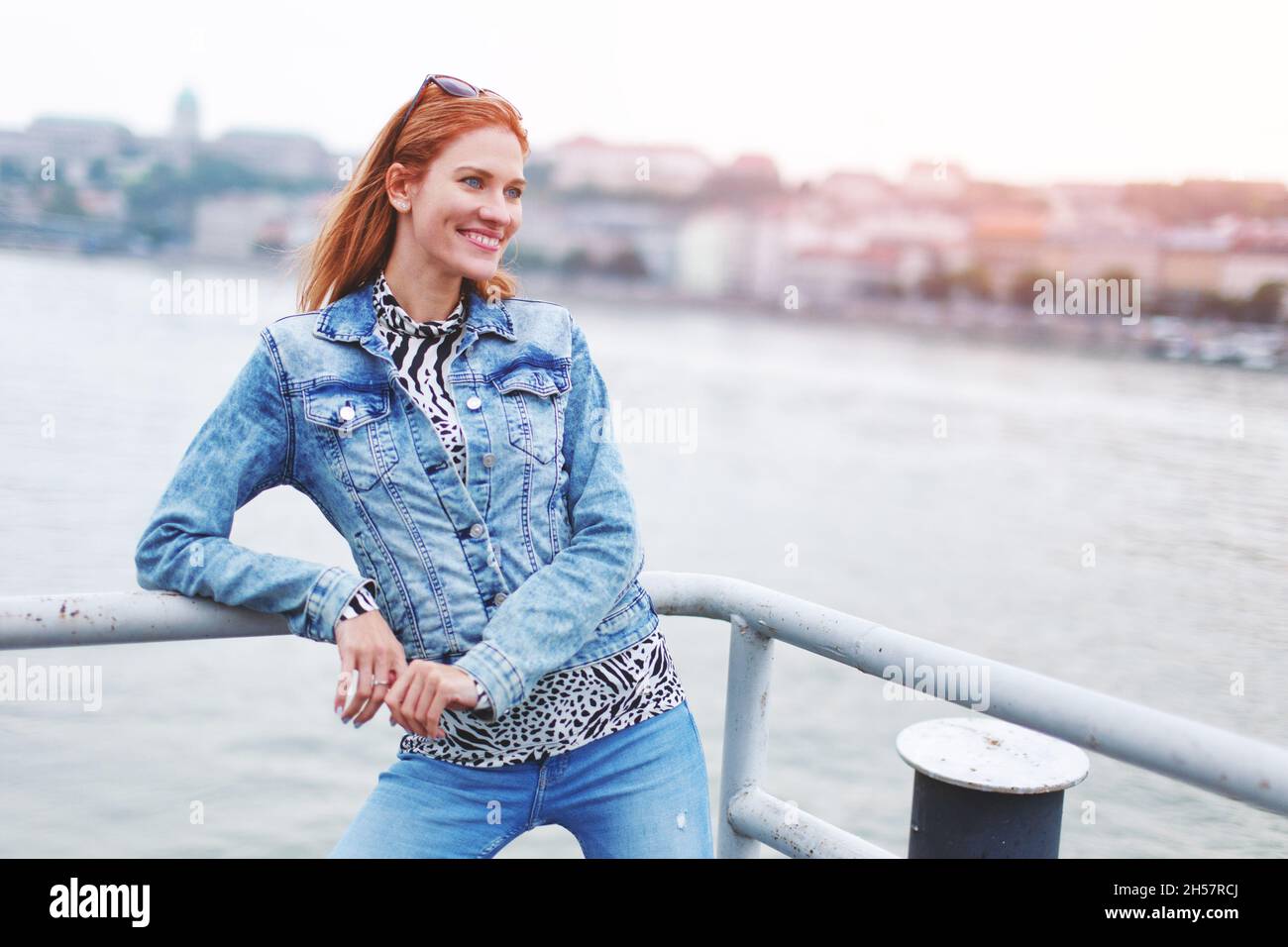 Glückliche junge Rotschopf kaukasische Frau posiert am Flussufer Seitenansicht Stockfoto