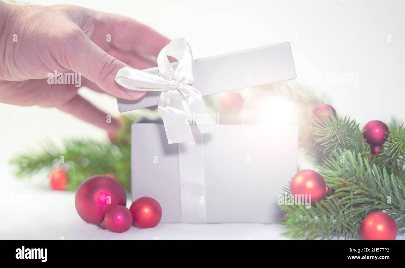 Hand öffnen Geschenkbox in Weihnachten. Rote Weihnachtskugel Ornamente und Tanne oder Kiefer Zweige. Stockfoto