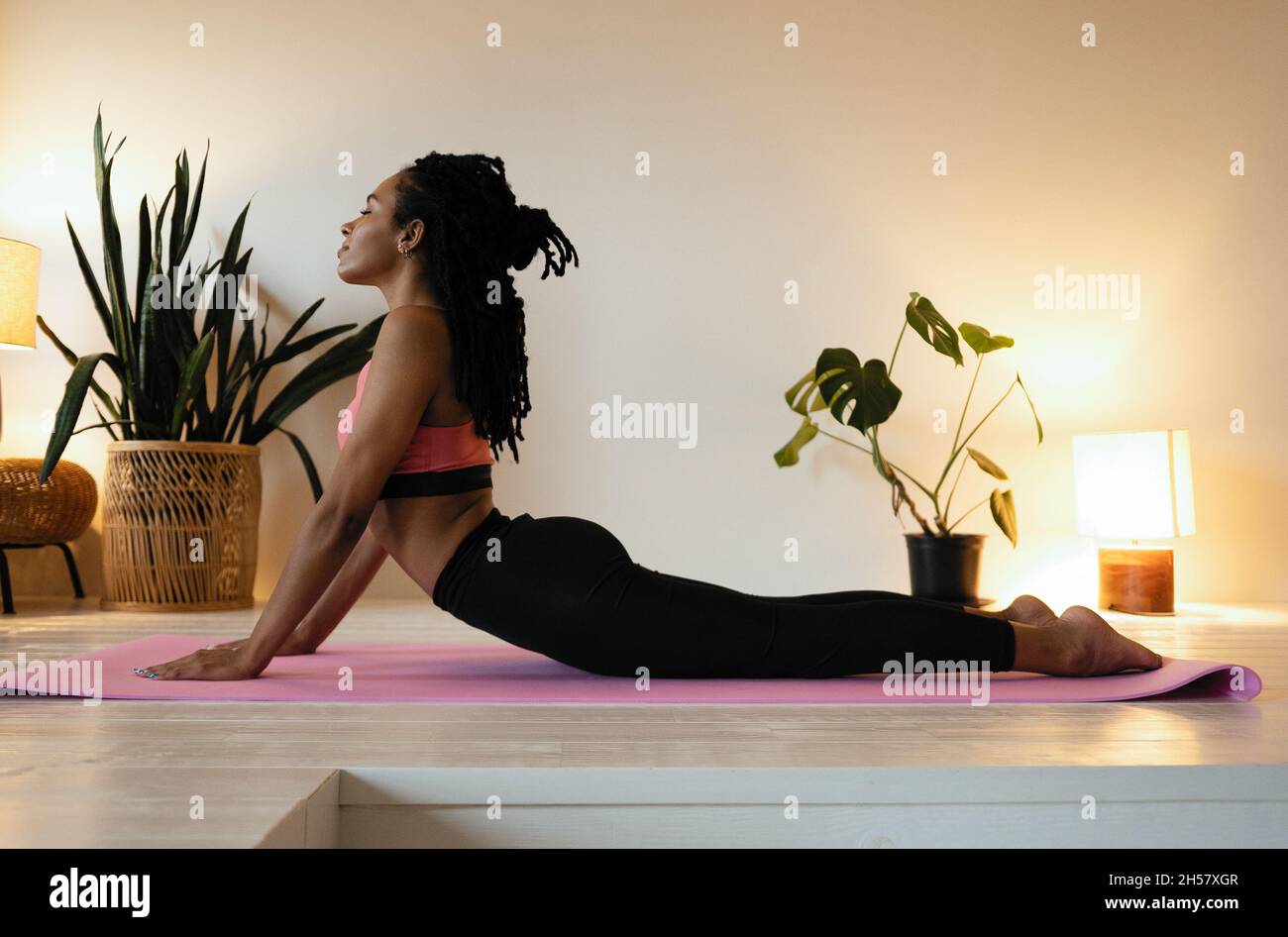 Zeit für Yoga. Attraktive und gesunde junge schwarze Frau, die Übungen macht, während sie sich zu Hause ausruht Stockfoto