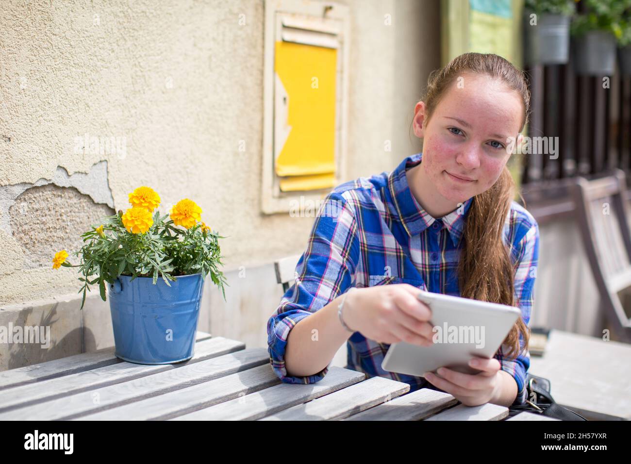 Teenager, die mit einem Tablet in der Cafeteria auf der Straße sitzt. Stockfoto