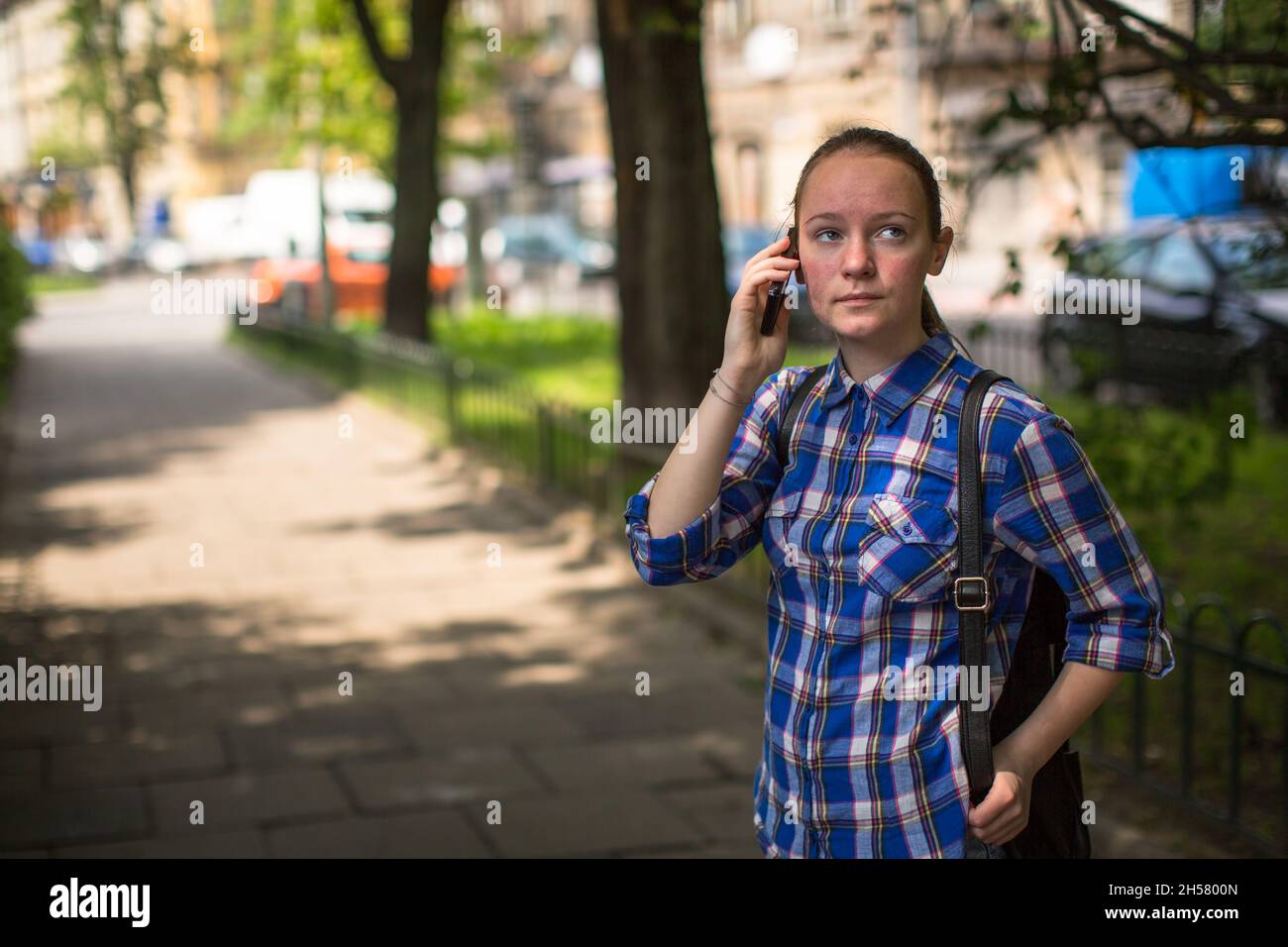 Ein Teenager-Mädchen, das in einem Sommerpark mit ihrem Handy spricht. Stockfoto