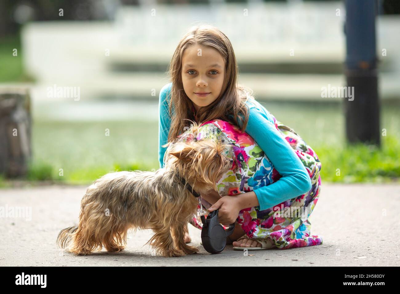 Ein Mädchen im Teenageralter mit einem kleinen Hund auf der Straße. Stockfoto