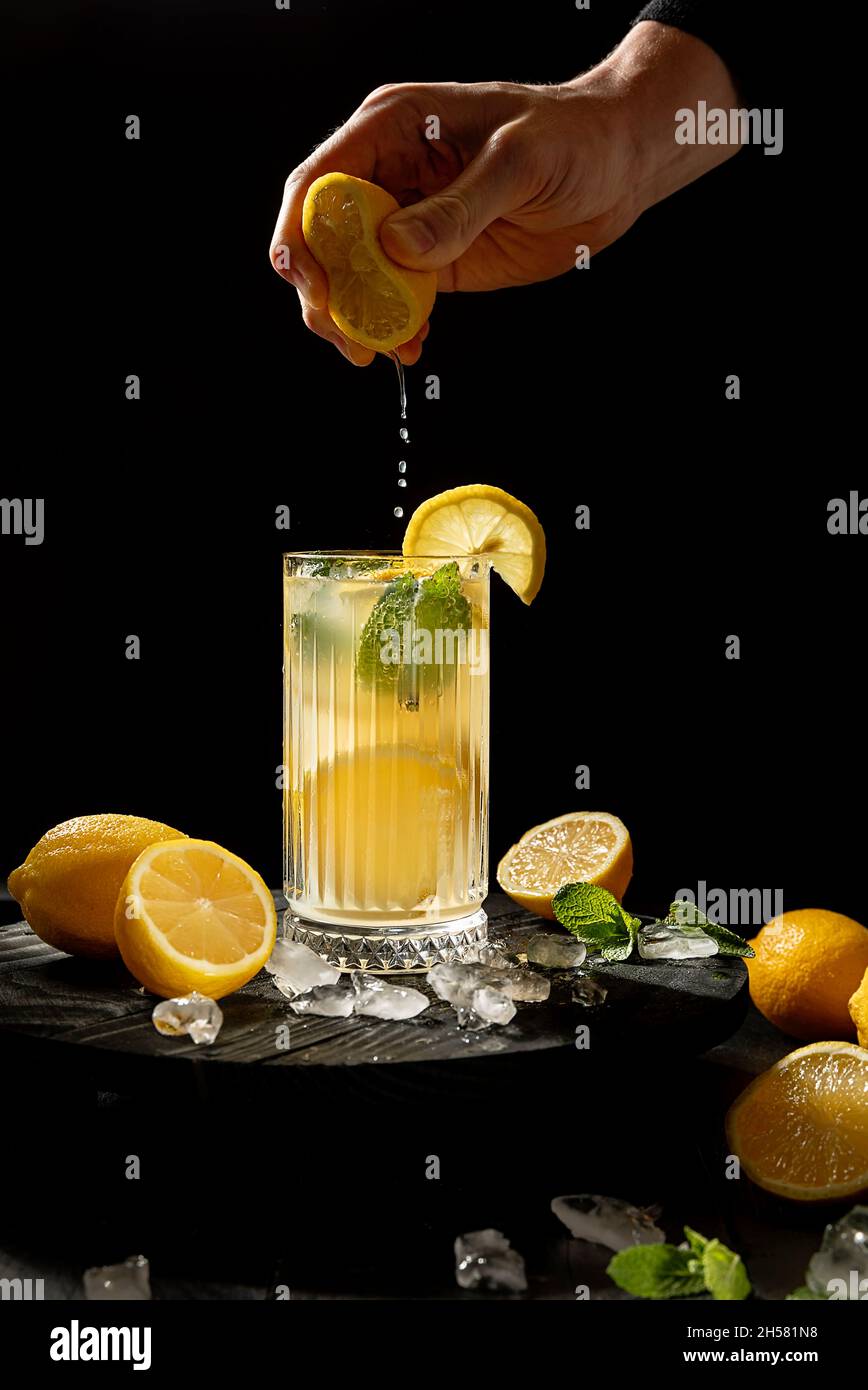 Zitrone in Glas mit Limonade auf schwarzem Hintergrund bespritzen Stockfoto