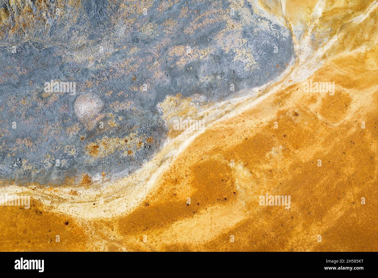 Graue und gelbe Farben von Kupferminenrückständen. Abstrakte natürliche Textur, Drohnenansicht direkt oben Stockfoto