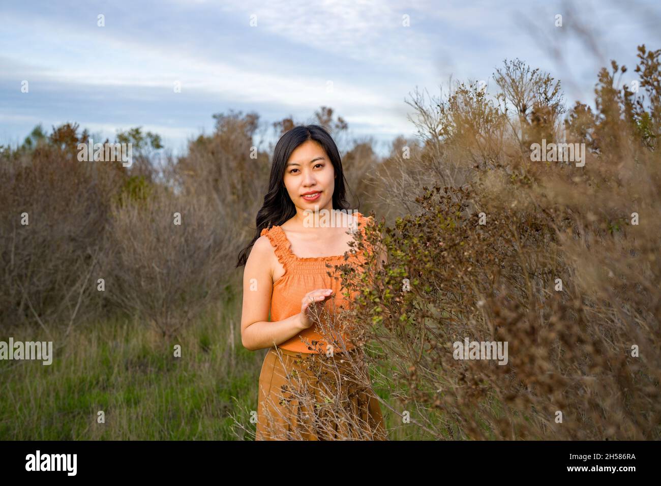 Junge asiatische Frau in Herbstfarben zu Fuß in den Sümpfen Stockfoto