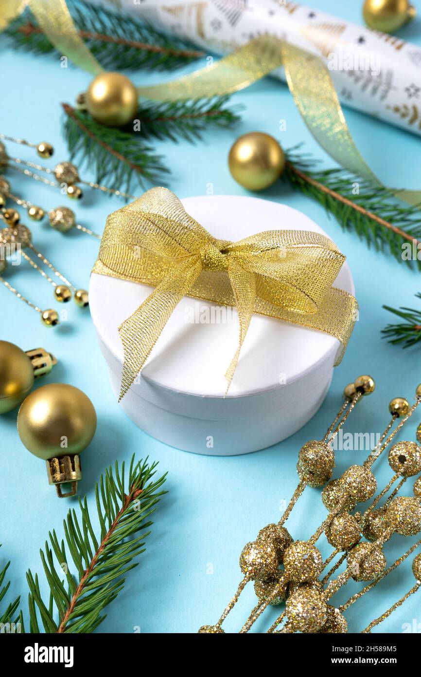 Geschenkbox mit goldenem Band. Weihnachtliche Golddekorationen auf hellblauem Hintergrund. Feiertags- und Feiertagskonzept für Postkarte oder Einladung. Side Vie Stockfoto