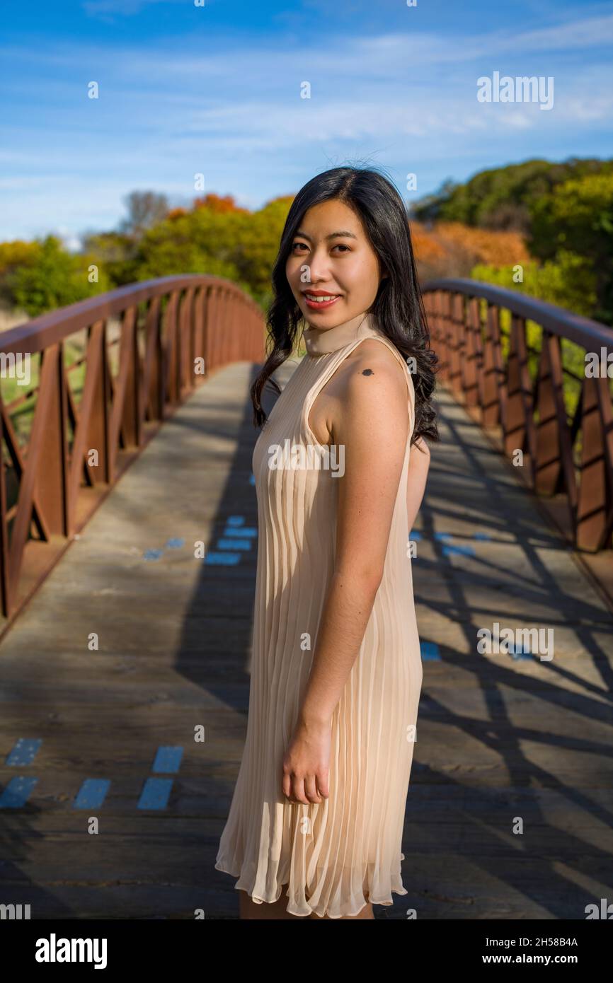 Junge asiatische Frau in einem Kleid auf einer Metall- und Holzbrücke in den Sümpfen Stockfoto