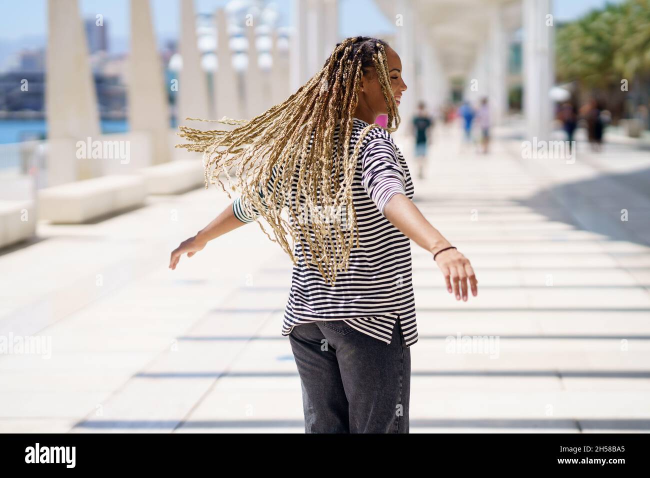 Junge schwarze Frau bewegt ihre farbigen Zöpfe im Wind. Typische afrikanische Frisur. Stockfoto