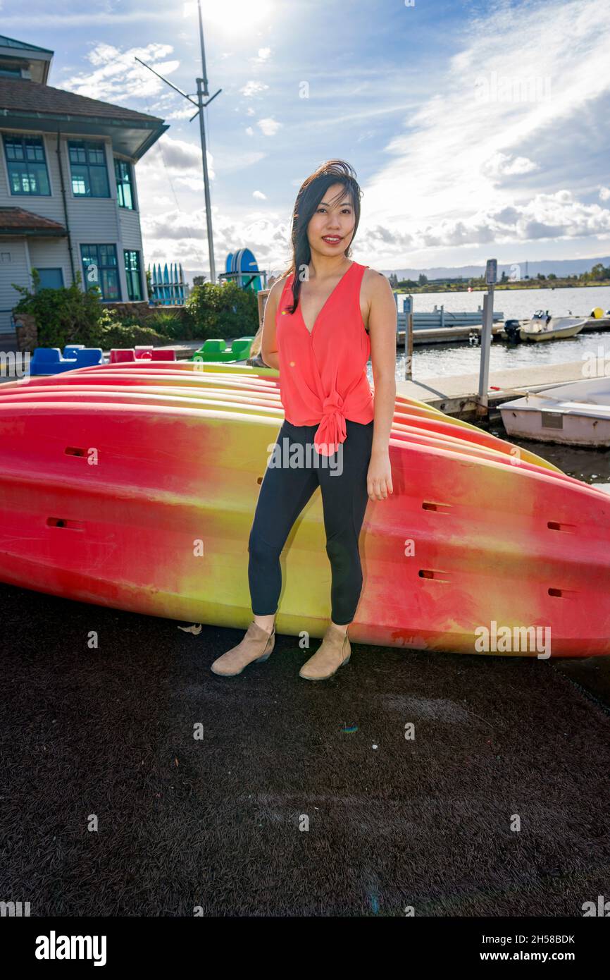 Junge asiatische Frau, die an einem See um ein Bootshaus herumläuft Stockfoto