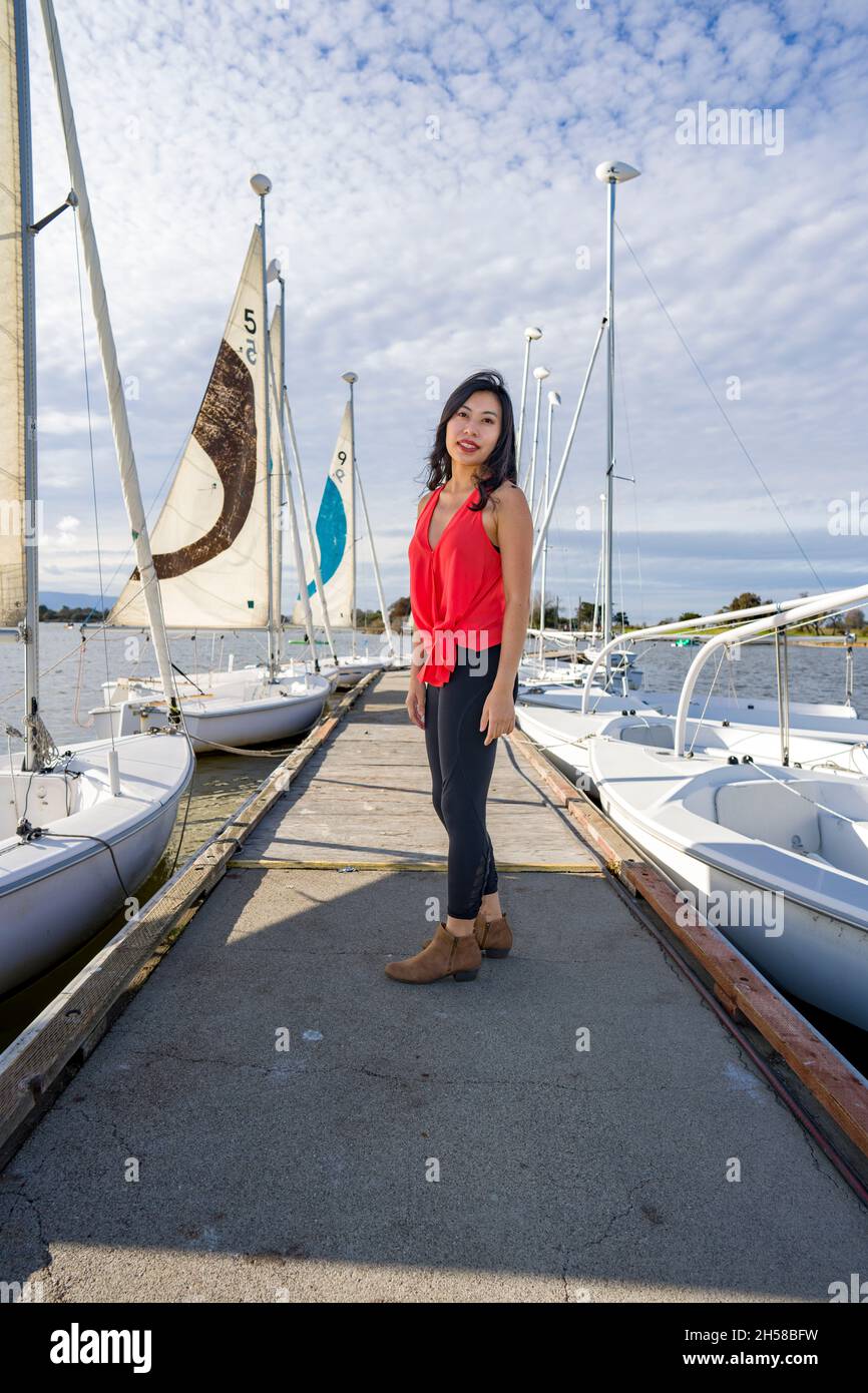 Junge asiatische Frau, die an einem See um ein Bootshaus herumläuft Stockfoto