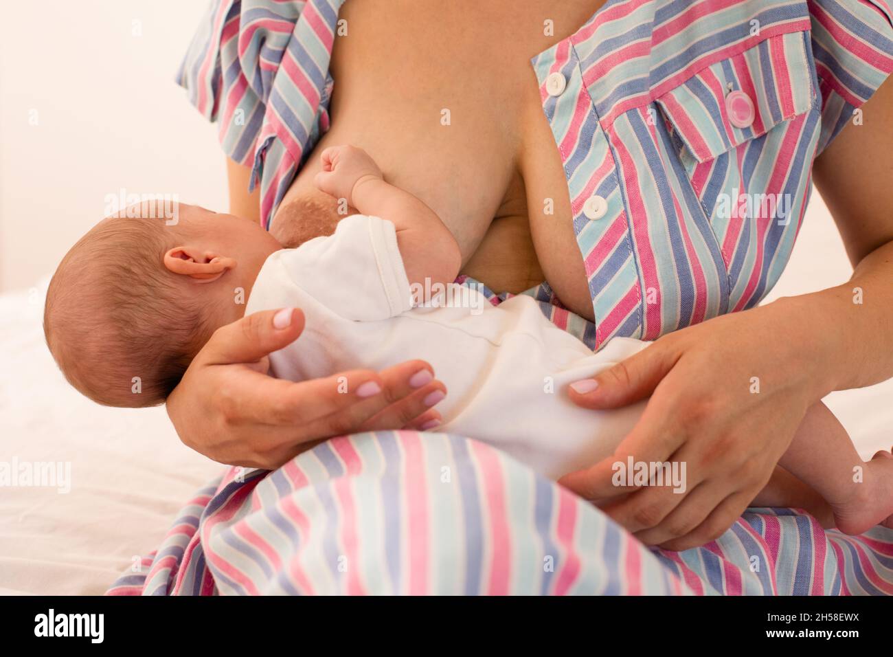 Die Mutter stillt ihr neugeborenes Baby auf dem Bett Stockfoto