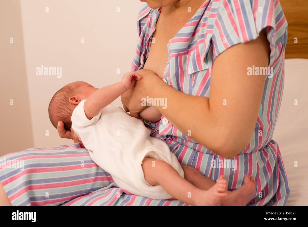 Die junge Mutter möchte ihr neugeborenes Baby stillen Stockfoto