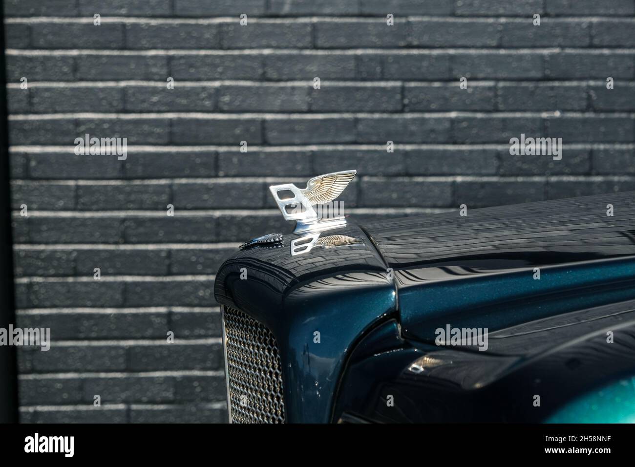 Kühlerfigur Flying B des Green Bentley Brooklands, geparkt an einer schwarzen Lagerhauswand Stockfoto