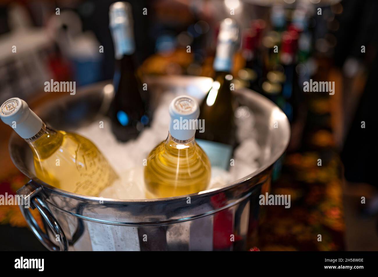 Weißwein wird in einem Eiskübel zusammen mit Rotwein auf dem Tisch gekühlt Stockfoto