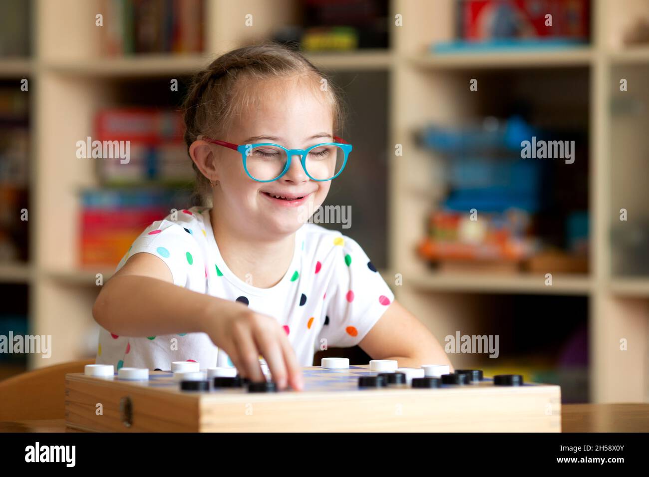Mädchen mit Down-Syndrom spielt mit ihrer Schwester in Quarantäne Checkers Stockfoto