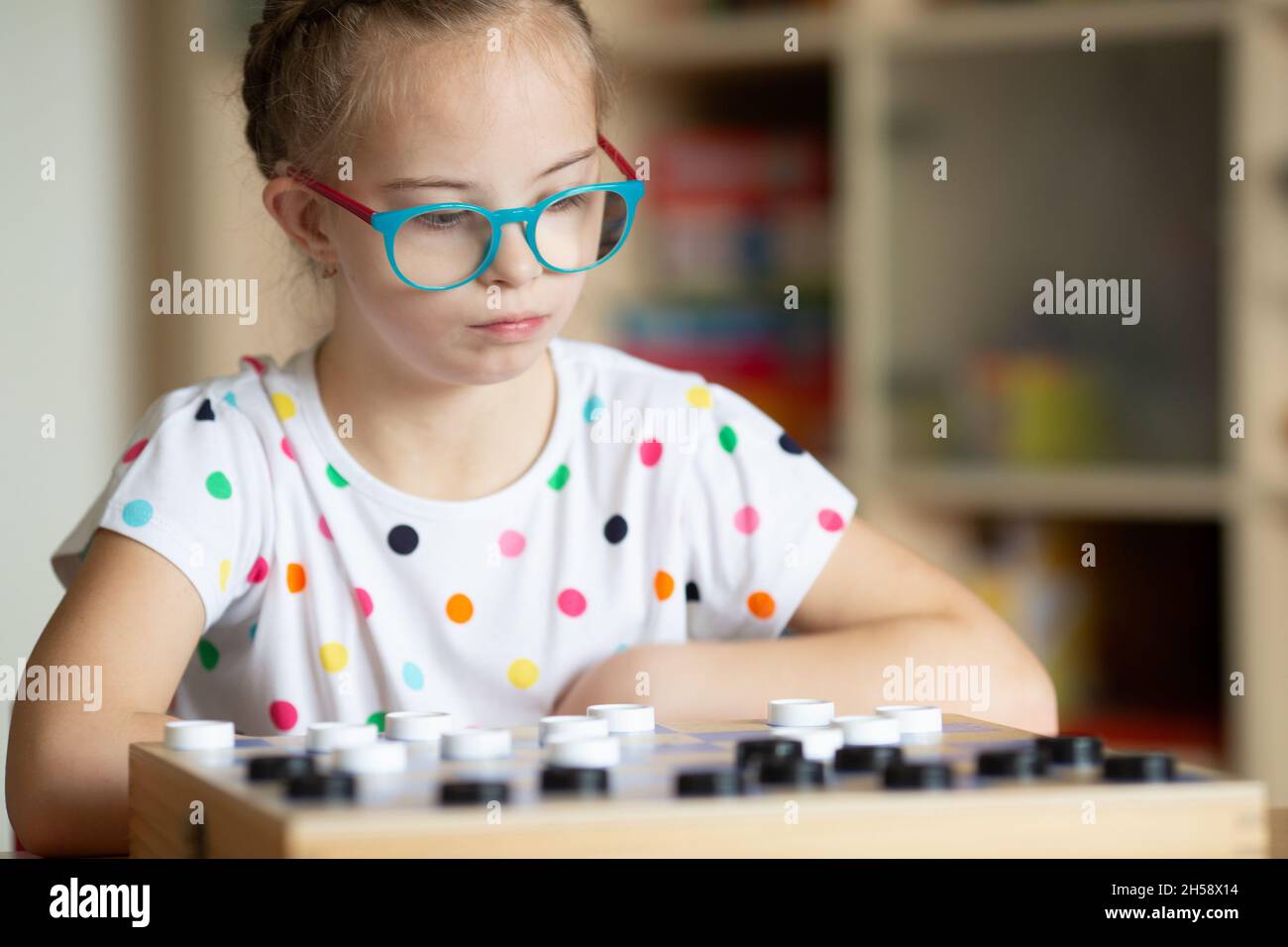 Mädchen mit Down-Syndrom spielt mit ihrer Schwester in Quarantäne Checkers Stockfoto