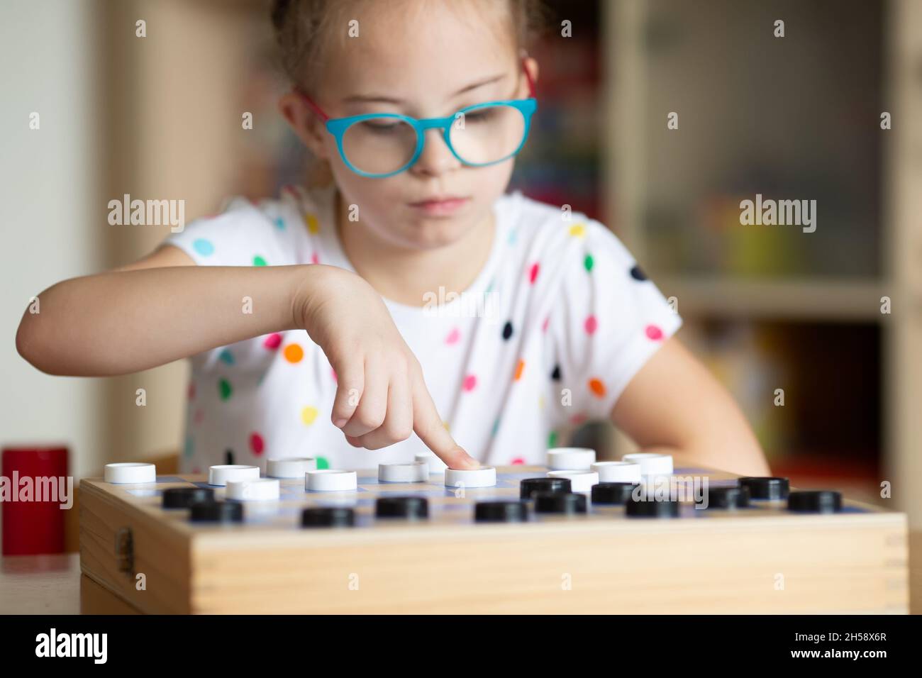 Mädchen mit Down-Syndrom spielt mit ihrer Schwester in Quarantäne Checkers Stockfoto