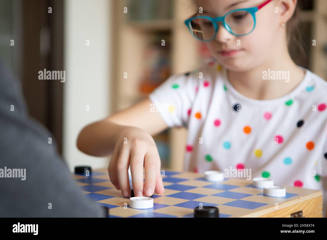 Mädchen mit Down-Syndrom spielt mit ihrer Schwester in Quarantäne Checkers Stockfoto