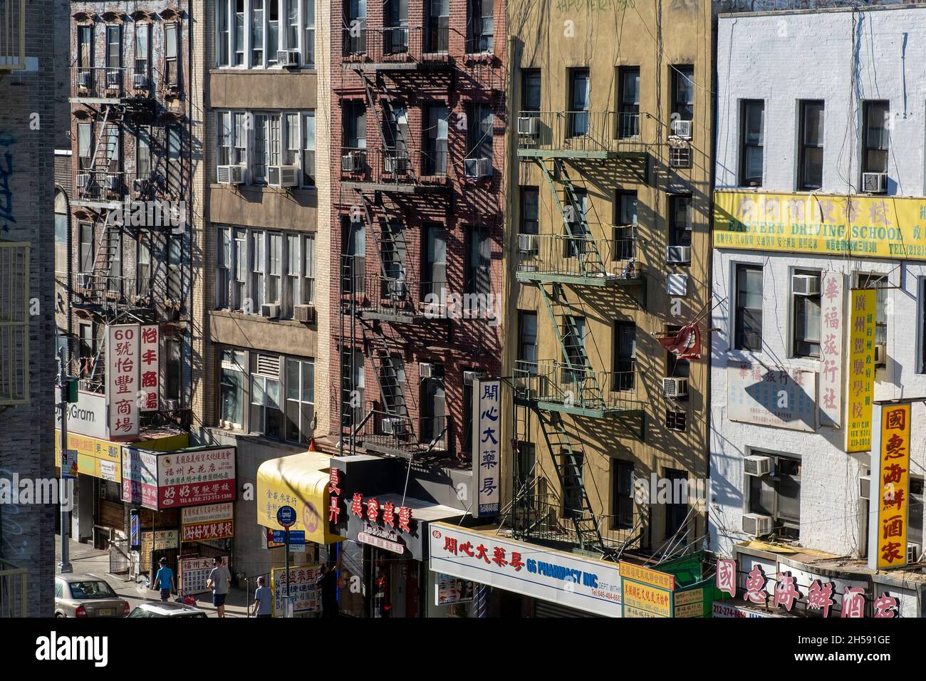 East Broadway, Chinatown, New York City, USA. 26. September 2021. Geschäftige Haupteinkaufsstraße in chinatown. Wohngebäude mit Geschäften auf Zaun Stockfoto