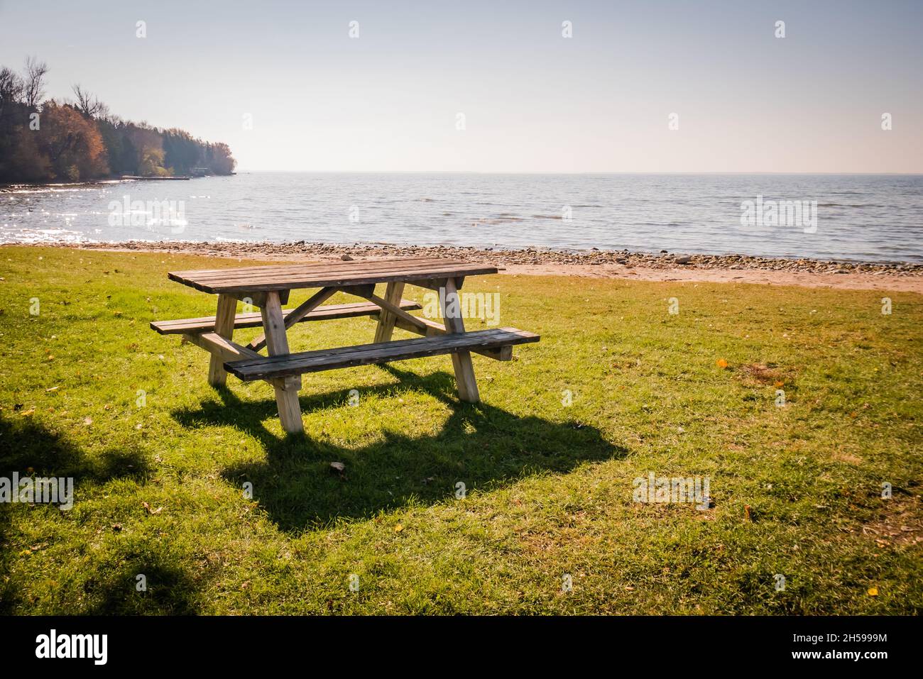 Leerer Picini-Tisch auf Gras mit Blick auf das Wasser Stockfoto