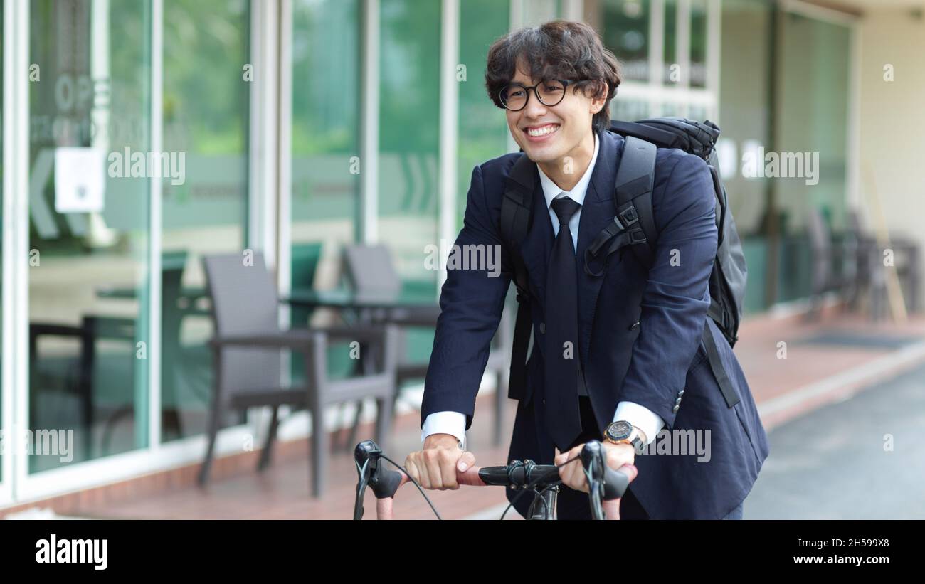 Glücklich und gut aussehend erfolgreiche asiatische junge Geschäftsmann Executive pendeln mit dem Fahrrad zu seinem Unternehmen. Stockfoto