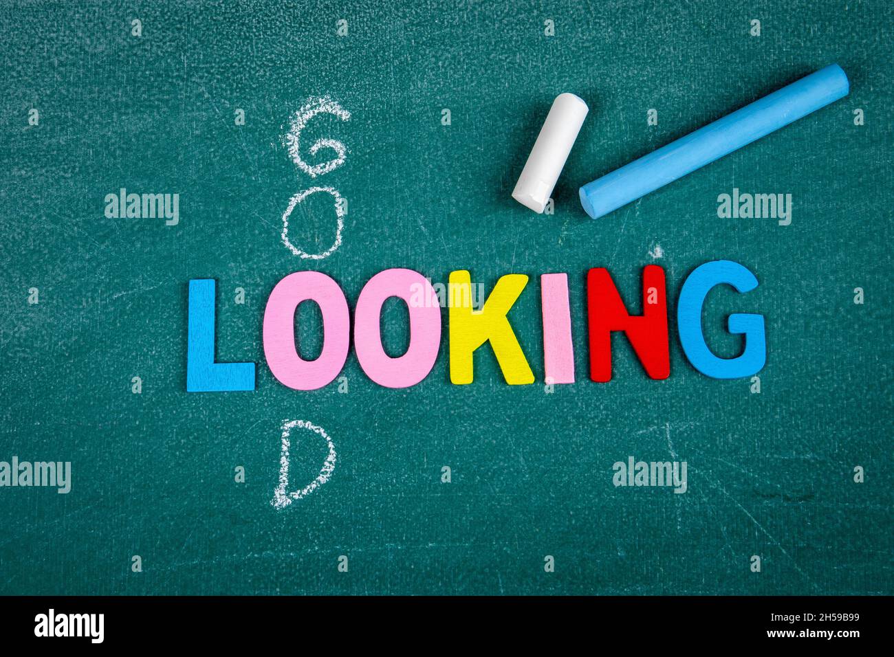 Gutes und aussehendes Konzept. Farbige Buchstaben und Kreidestücke auf der Tafel. Stockfoto