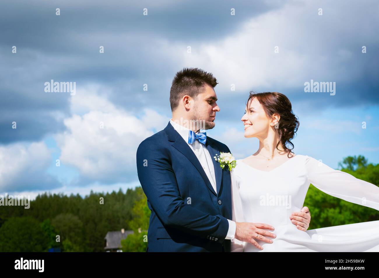 Glücklich litauischen Hochzeitspaar stehen zusammen im Freien in Smart Kleidung Pose mit trüben dramatischen blauen Himmel Hintergrund Stockfoto Glücklich litauischen Hochzeitspaar stehen zusammen im Freien in Smart Kleidung Pose mit trüben dramatischen blauen Himmel Hintergrund Stockfoto