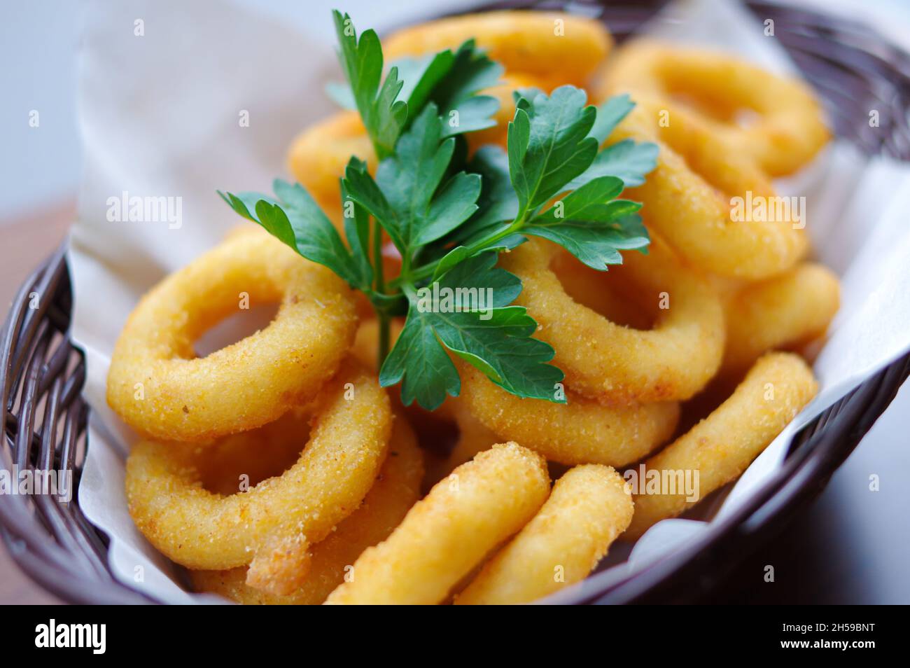 Goldene Farbe tief gebrannt knusprigen Zwiebelring Calamari Ringe mit Koriander Fast Food Nahaufnahme Ansicht Stockfoto