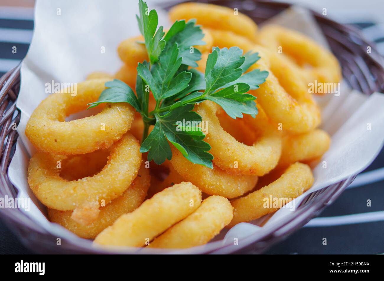 Goldene Farbe tief gebrannt knusprigen Zwiebelring Calamari Ringe mit Koriander Fast Food Nahaufnahme Ansicht Stockfoto