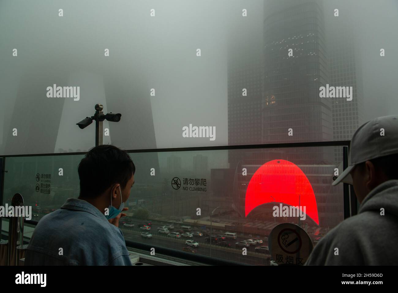 Zwei Männer schauen sich die Hochhäuser im zentralen Geschäftsviertel (CBD) von Peking an, die von starkem Smog in Peking, China, umhüllt sind. 06-Nov-2021 Stockfoto